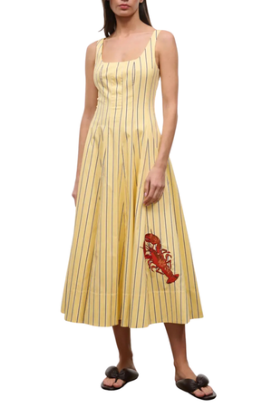 Woman wearing a long yellow striped dress with a red lobster design on a white background