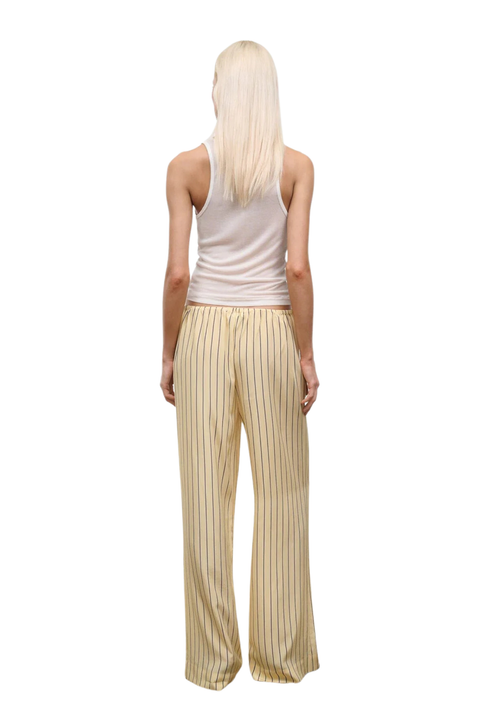 Woman wearing a yellow striped two piece pants and sleeveless top set on a white background back angle