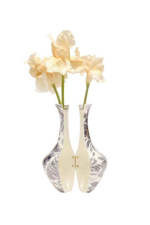 Two small white ceramic bud vases with a subtle gray marbled pattern, each holding a pale cream iris flower, set against a solid white background.