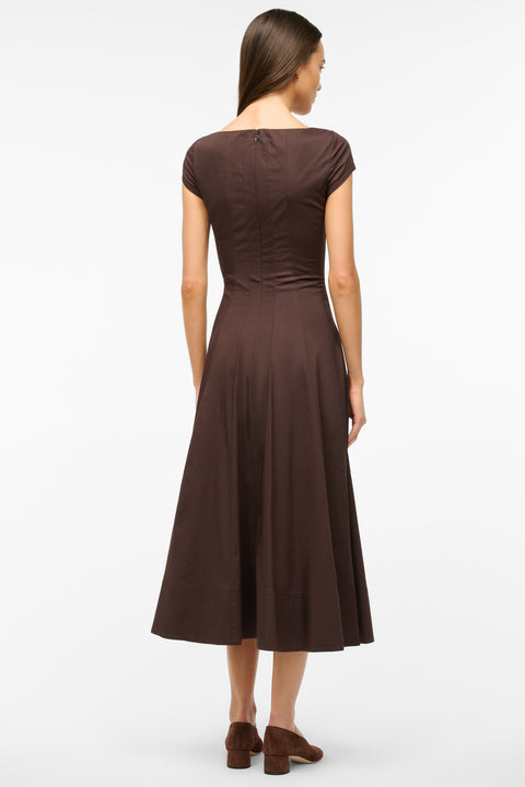 Back view of a woman wearing a brown midi dress that features cap sleeves, a square neck, corset styles paneling, and an A-line skirt, paired with brown heels. 