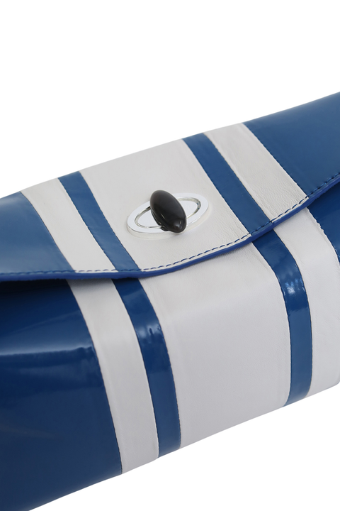 A close-up of a glossy blue and white striped shoulder bag with a flap closure and a black oval ring detail.