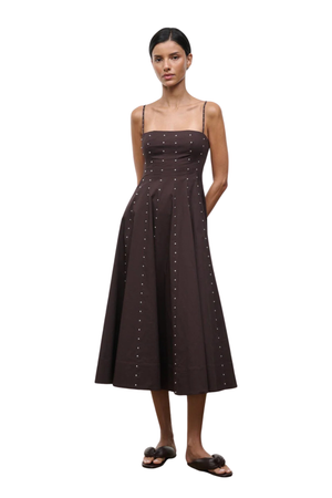 Woman wearing a long brown dress with silver studs on a white background
