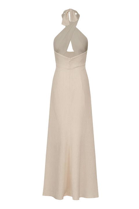 An ankle-length halter-neck dress in a light beige or cream color, featuring a crossover front neckline with a keyhole cutout