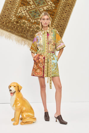 Woman wearing a multicolor, printed, mini shirtdress that features a point collar and self-tie belt, paired with brown mules. 