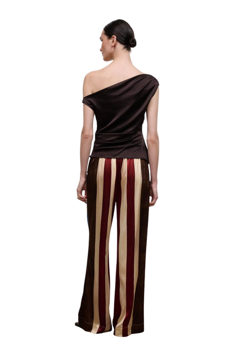 A woman shown from the back wearing a dark brown one-shoulder top and matching wide-leg pants with vertical cream and burgundy stripes, against a plain white background.