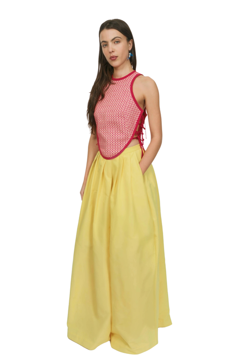 A woman wearing a patterned red top and a yellow long skirt