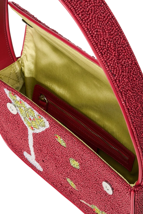 Close-up of a red textured handbag with a martini glass embroidered design on the front, showing a green satin interior and zipper pocket.