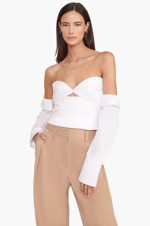 Model wearing the white off the shoulder top with the removable sleeves and facing the camera