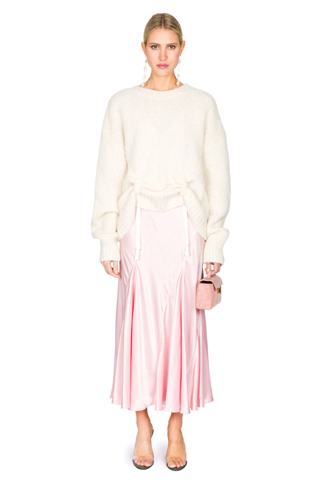 White knit sweater with low hanging ties paired with a pink evening gown