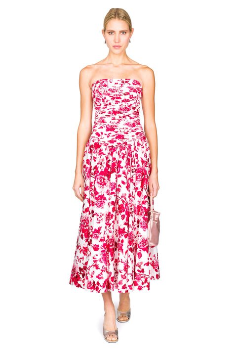 Woman walking forward wearing a strapless floral dress on a white background.