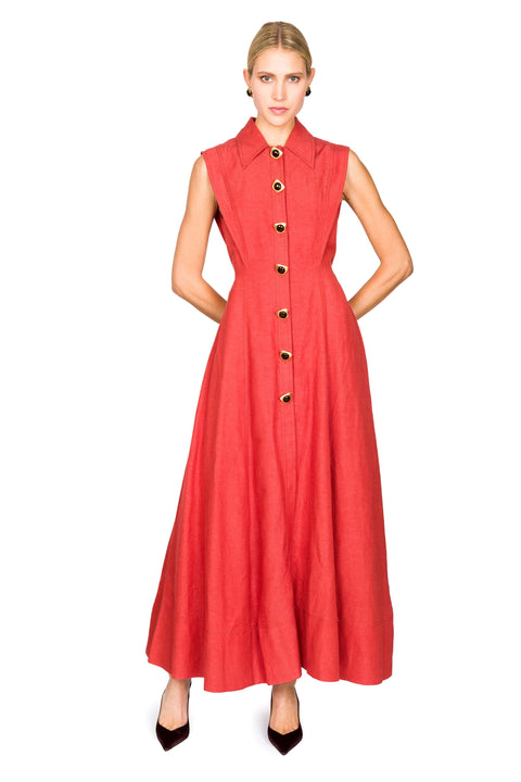 Woman posing with arms behind back wearing a red sleeveless dress with buttons on a white background