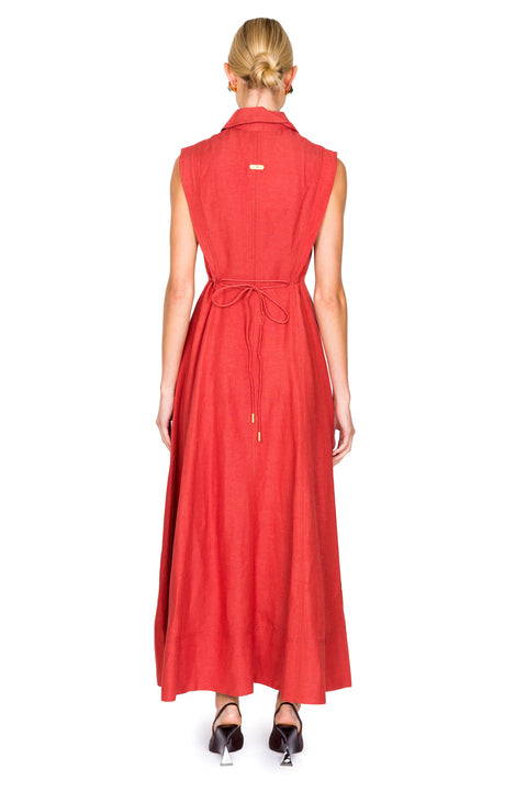 Woman facing away wearing a red maxi sleeveless dress with tie on a white background.