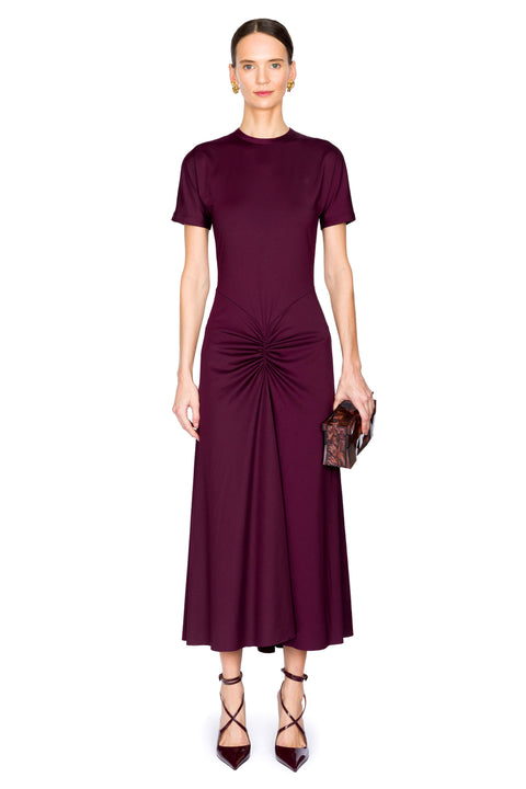 Woman wearing a burgundy satin midi dress with a scrunch detail on a white background