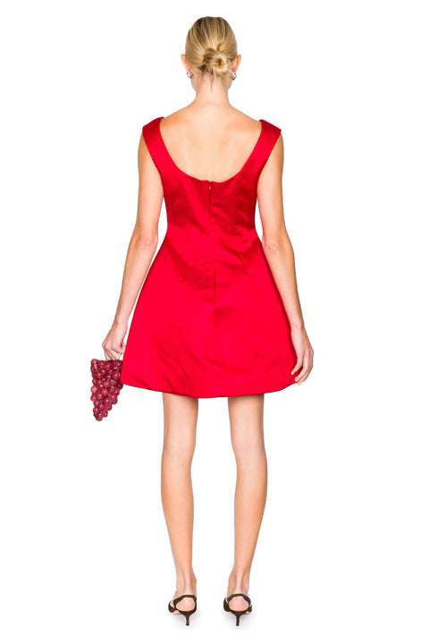 Back of woman wearing a red mini dress holding a clutch on a white background