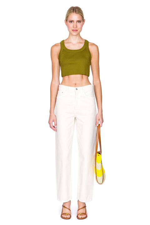 Woman wears green cropped tank top with raw hem and cream jeans.