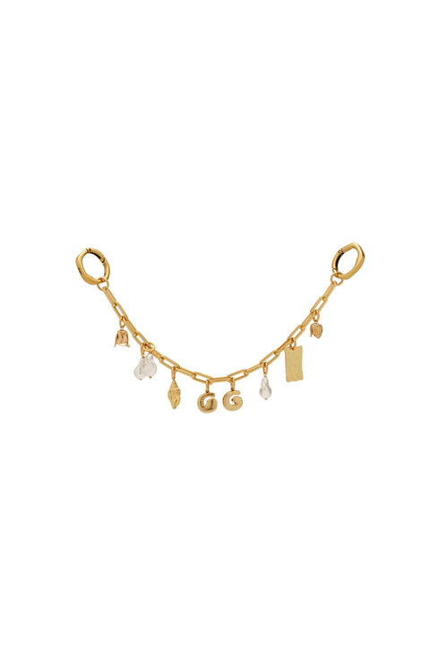 Gold bag chain with various charms on a light beige background