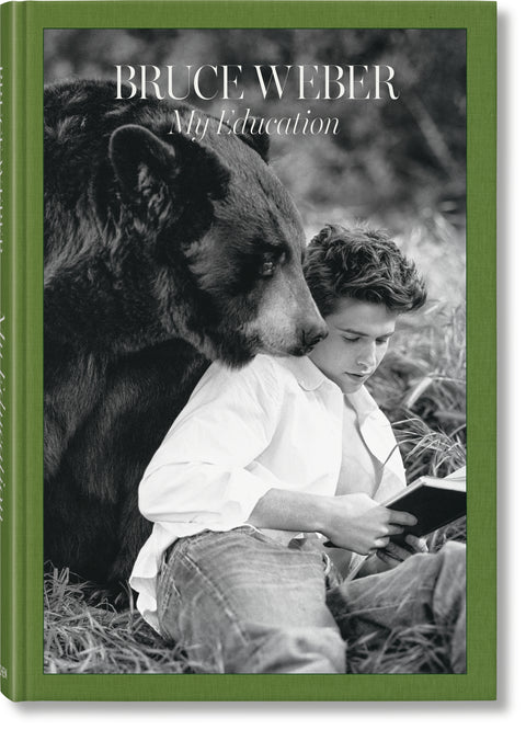 Cover of a coffee table book titled "Bruce Weber: My Education" that features a black and white photo of a man sitting next to a bear with a green border. 