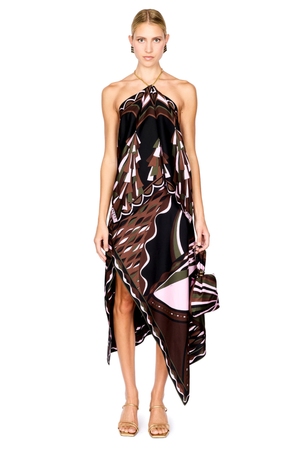 A model wearing a halter-neck, asymmetrical top and midi skirt with a brown, black, and pink abstract pattern, holding a matching handbag against a white background.