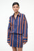Close up of a woman wearing a blue and orange striped long sleeve mini dress. 