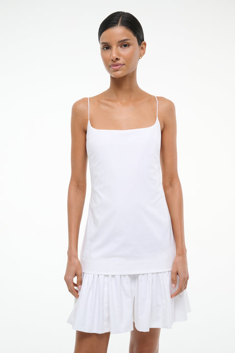 Close up of a woman wearing a sleeveless white mini dress with a layered effect. 