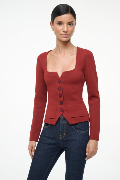 Woman wearing a red cardigan and blue jeans on a white background
