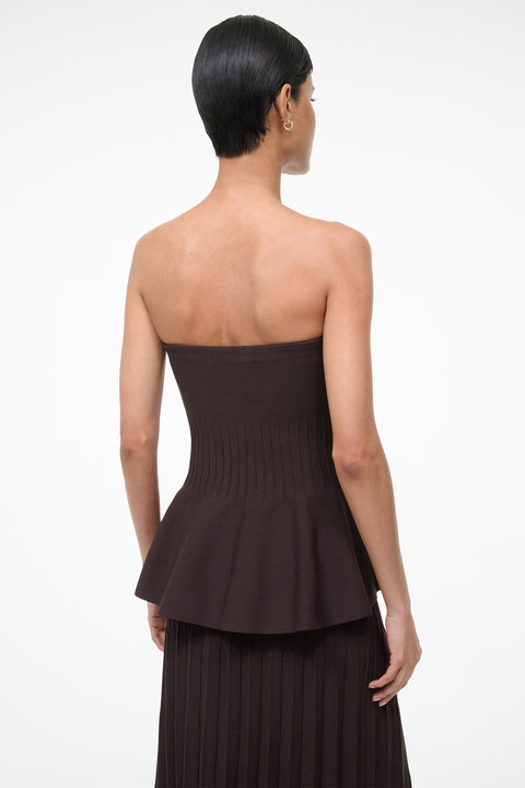 back-facing woman wearing a brown knit, strapless peplum top with a matching skirt. 