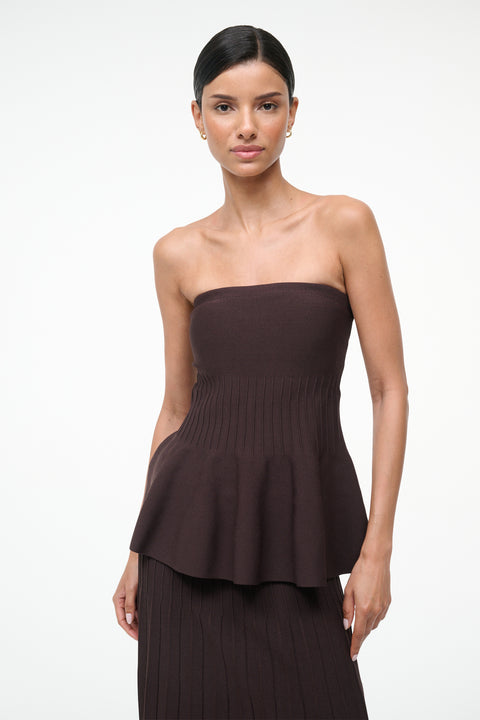 Close up of a woman wearing a brown knit, strapless peplum top with a matching skirt. 