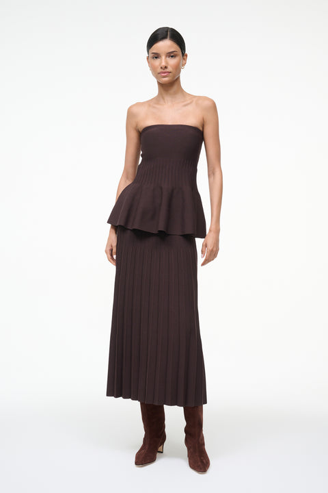 Woman wearing a brown knit, strapless peplum top with a matching skirt. 