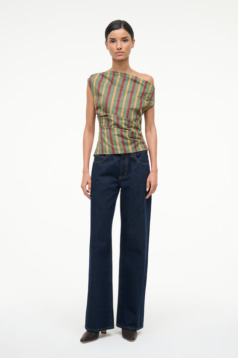 Woman wearing a colorful striped top and dark blue jeans on a white background