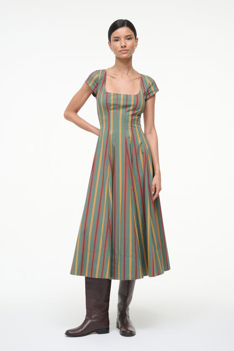 Woman wearing a green, red, and yellow striped midi dress with cap sleeves and a square neck with brown boots. 