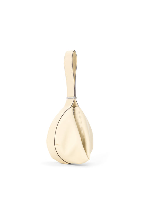 Side angle of a cream handbag folded together with a silver buckle. 