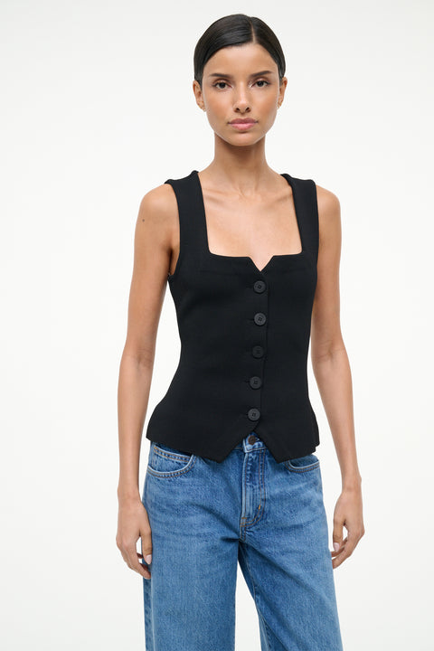 Woman wearing a black sleeveless top and blue jeans on a white background