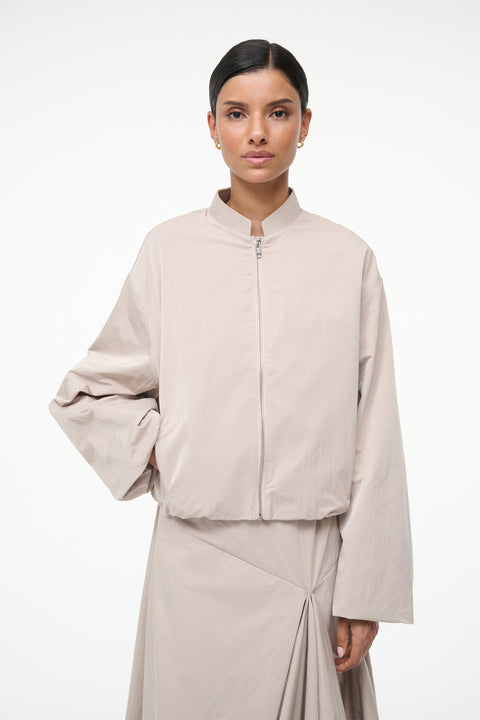 Woman wearing a beige jacket and skirt set on a white background
