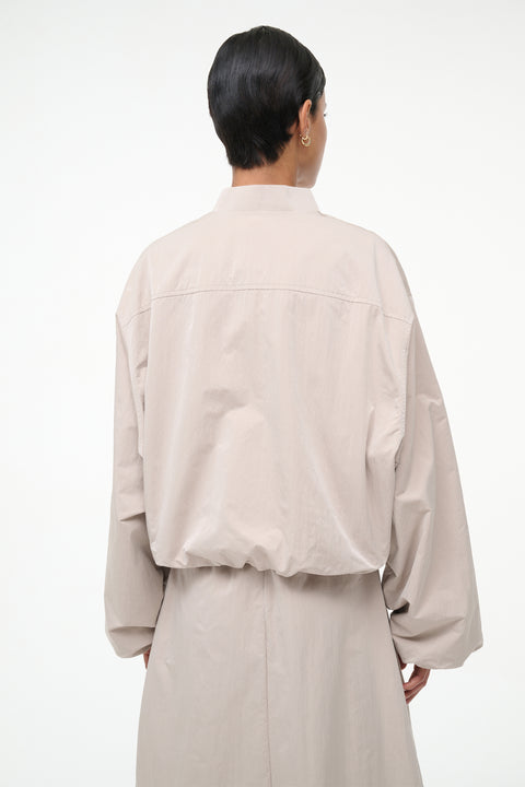 Person wearing a beige jacket and skirt set on a white background