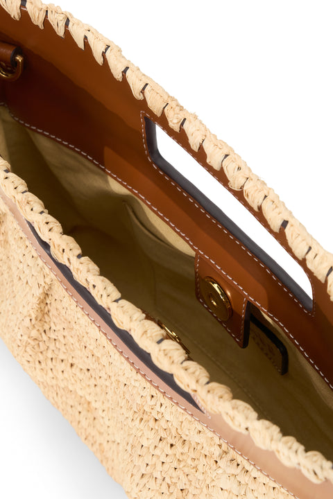 Close-up of a straw handbag with a brown handle on a white background