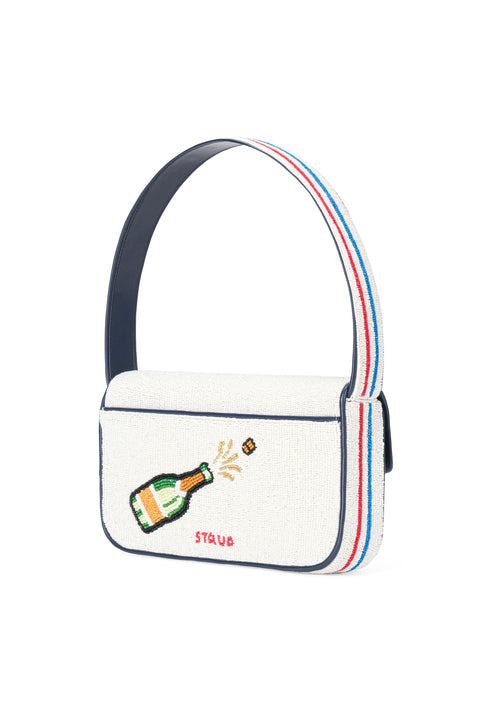 Back of a white beaded handbag with champagne bottle design on a white and red and blue stripe shoulder strap.