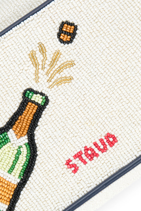 Detail shot of a cork popping out of a champagne bottle on the back of a white beaded handbag. 