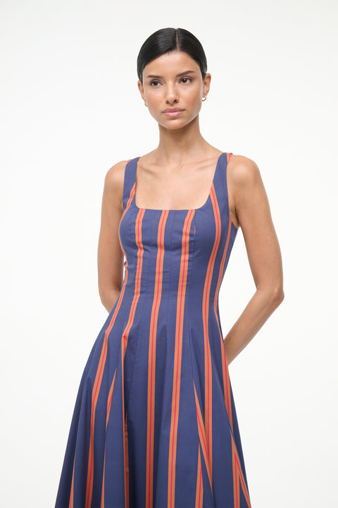 Close up of a woman wearing a blue and orange striped sleeveless midi dress with auburn suede boots. 