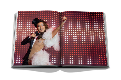 Open book showing a person in a theatrical costume on a red and white patterned background