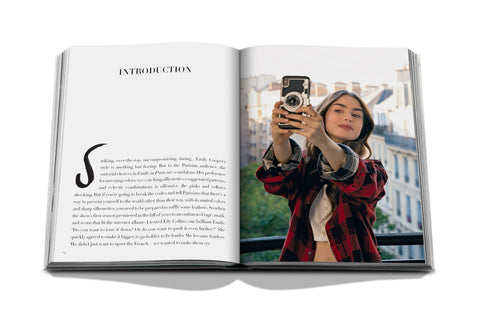 Open book with text and a photo of a Emily in Paris holding a camera, set against an urban background.