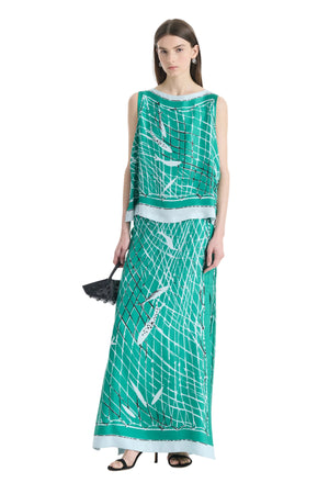 Woman wearing a green patterned top and maxi skirt on a white background