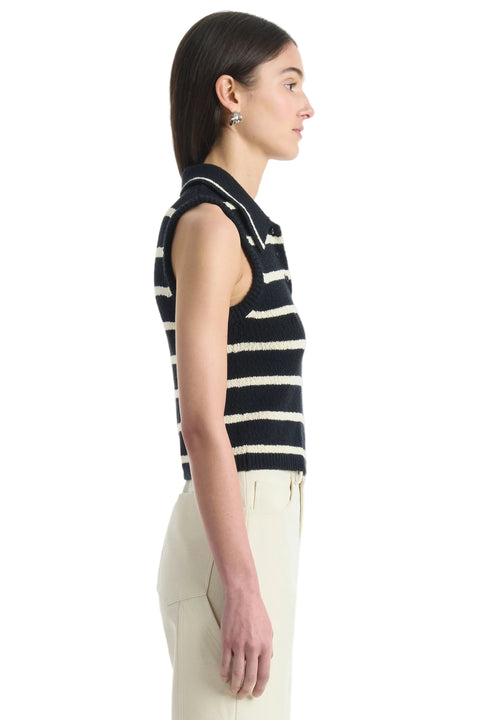 Woman facing the right wearing a black and white striped sleeveless top on a white background