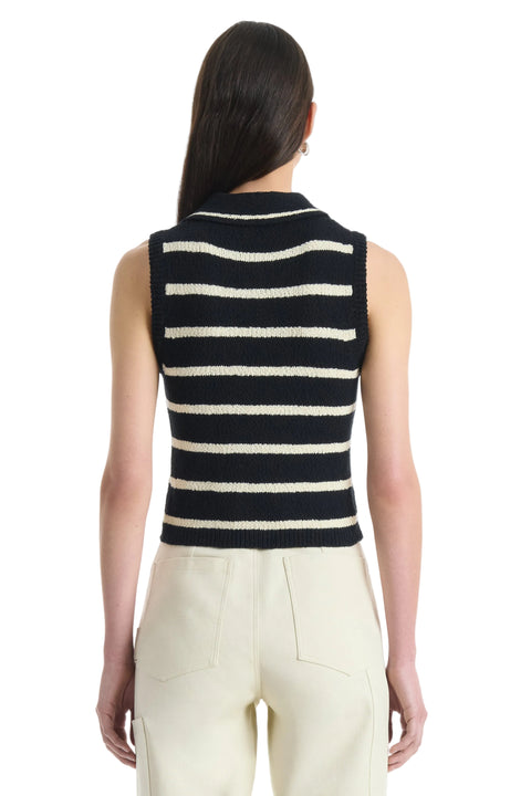 Back of Woman wearing a black and white striped sleeveless top with beige pants on a white background