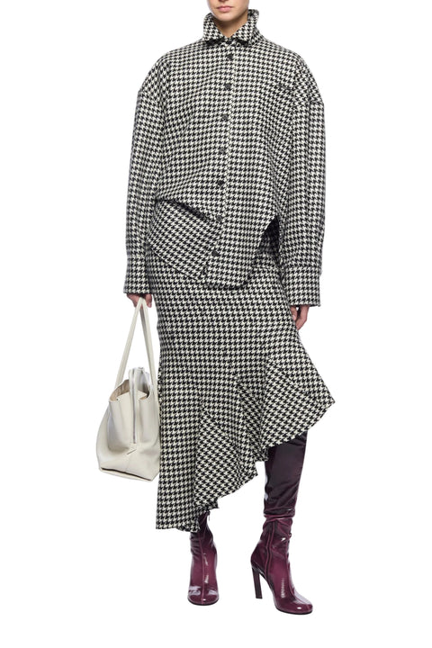 Person wearing a black and white checkered outfit with a white bag on a white background