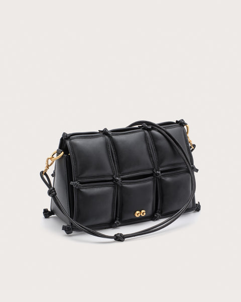Black quilted handbag with gold accents and a strap. 