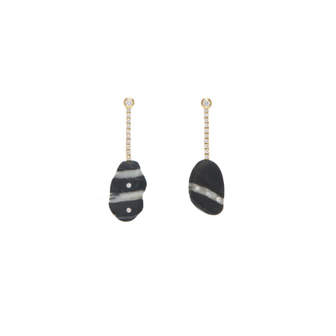 A pair of drop earrings that feature two irregular black and white stones embellished by small round diamonds, hanging from a pave diamond stud post. 