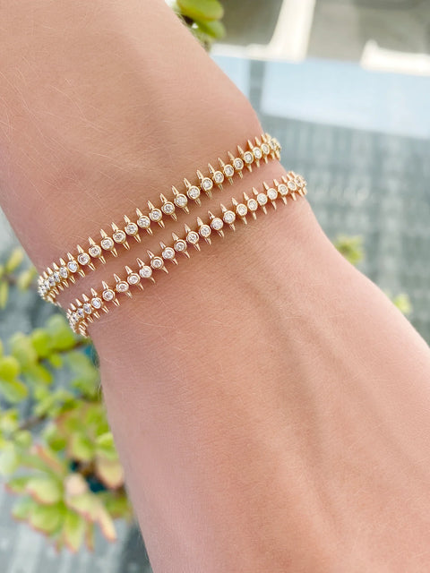 Model arm wearing two orbis gold tennis bracelets.