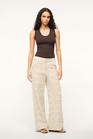 Woman wearing ivory tweed wide leg pants, paired with a brown tank top.