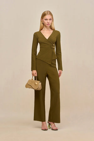 Woman wearing a green ribbed long sleeve top that features a V-neck and a wrap detail secured with gold-toned hardware, paired with matching wide leg pants. 