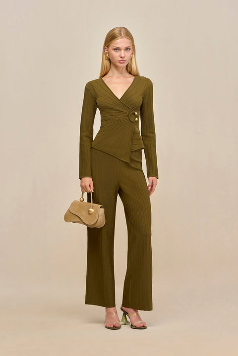 Woman wearing a green ribbed long sleeve top that features a V-neck and a wrap detail secured with gold-toned hardware, paired with matching wide leg pants. 